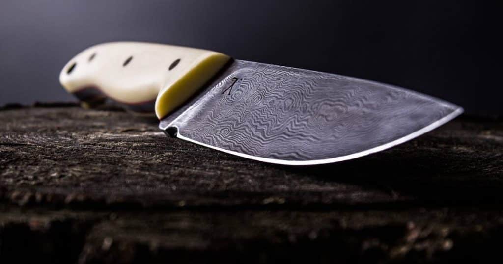 un artisan forgeron montrant comment forger un couteau avec une chaine de tronçonneuse pour faire un couteau damas
